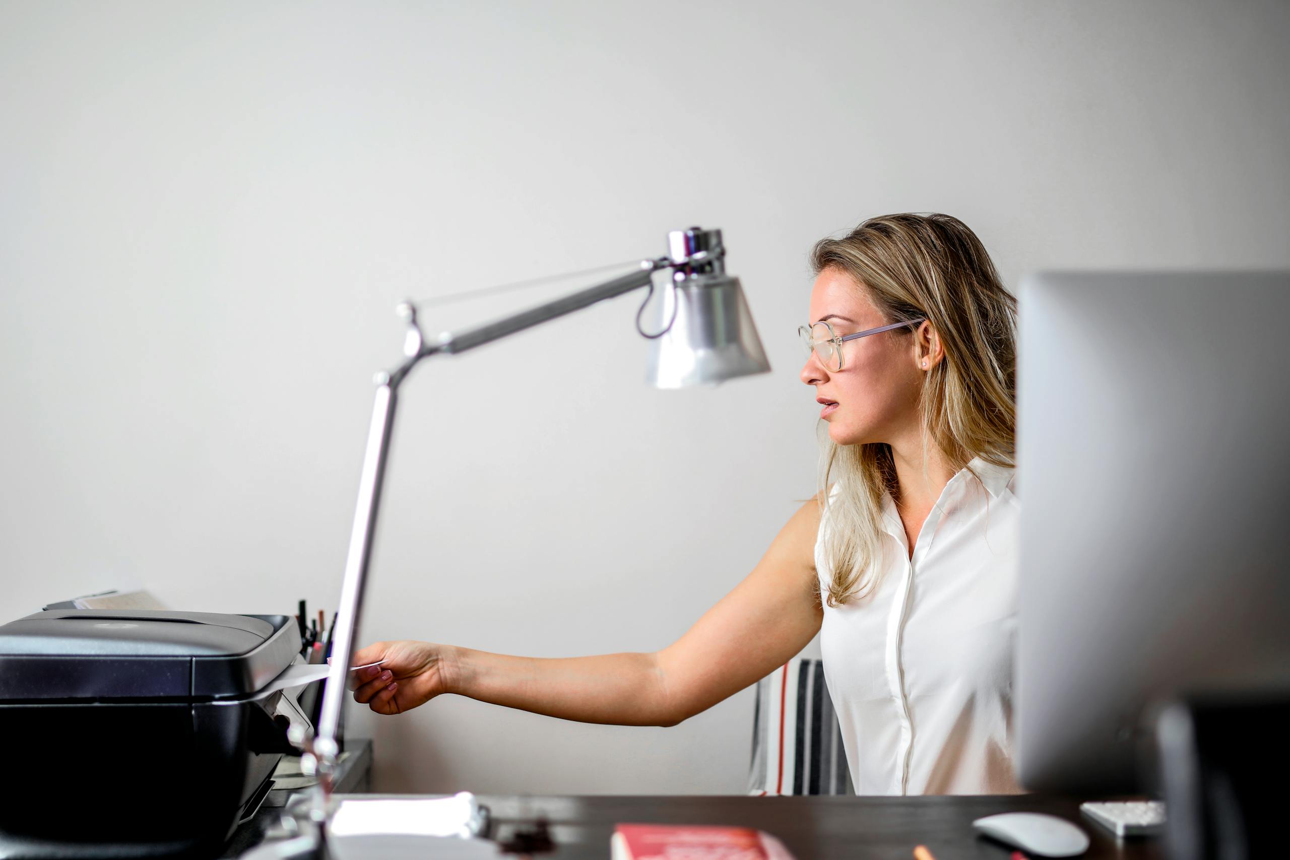 Woman in modern office setting using printer, blending technology with contemporary style.