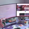 Stylish desk setup with dual monitors, keyboard, headphones, and cozy decor for tech enthusiasts.